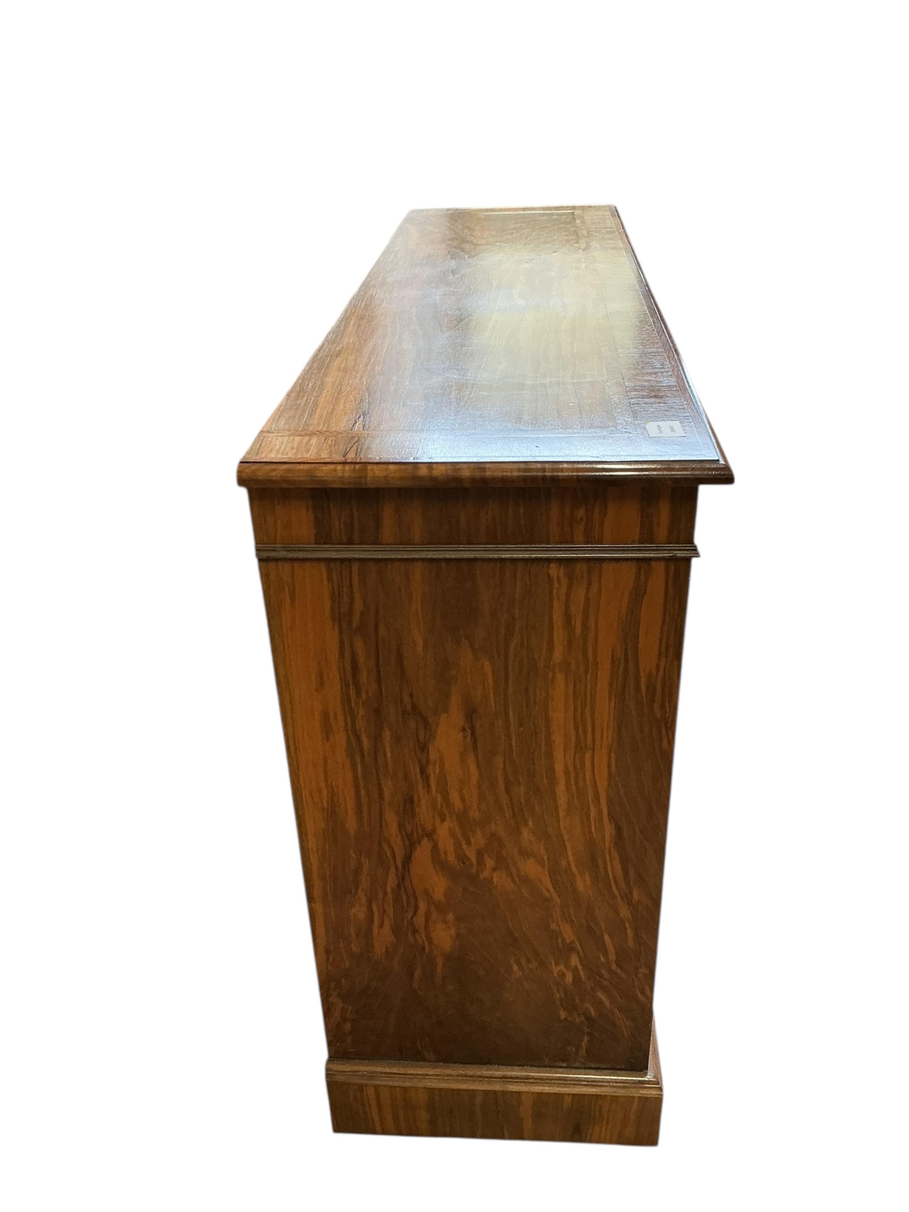 A Regency style feather banded walnut dwarf open bookcase, width 140cm, depth 42cm, height 94cm